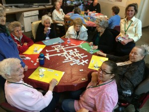 Seniors sitting around a table playing dominoes and talking with each other